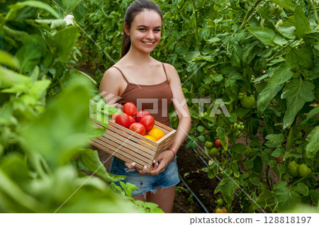 Girl holding wooden box with tomatoes Girl holding wooden box with tomatoes 128818197