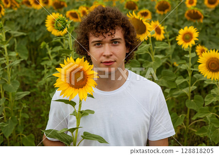 Man in white t-shirt holding sunflower flower 128818205