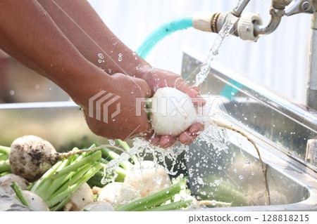 A man washing harvested turnips 128818215