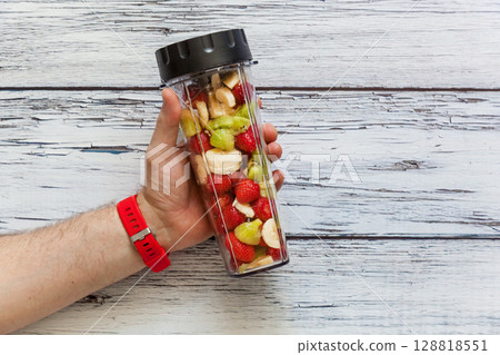Hand holding blender cup with fresh fruit mix 128818551