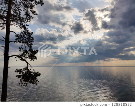 Peaceful lake view with dramatic cloudy sky and sun rays 128818552