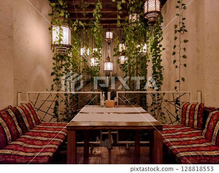 Cozy restaurant interior with hanging lanterns and green vines 128818553
