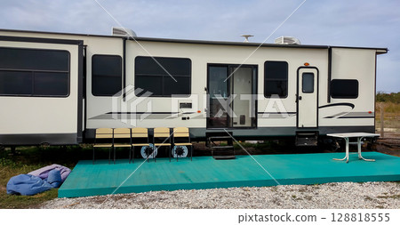 Modern travel trailer with green deck and outdoor seating 128818555