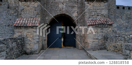 Medieval stone fortress gate with arched entrance and iron doors 128818558