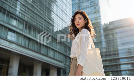A Japanese woman in business casual attire walking through an urban office district: "Generative AI" 128819611