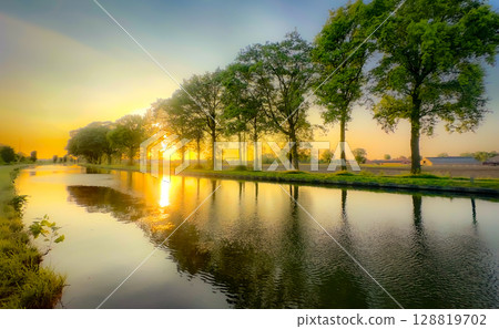 A Tranquil Sunset Reflection that casts a beautiful glow over a Serene and Calm Canal A Tranquil Sunset Reflection that casts a beautiful glow over a Serene and Calm Canal 128819702