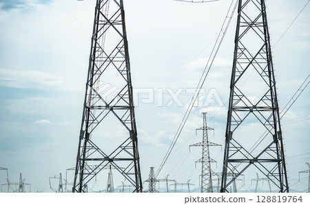 High voltage power lines and electrical towers against a clear sky for electricity distribution High voltage power lines and electrical towers against a clear sky for electricity distribution 128819764