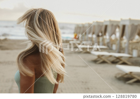 Blonde Woman Turning on Beach in Summer Breeze 128819780