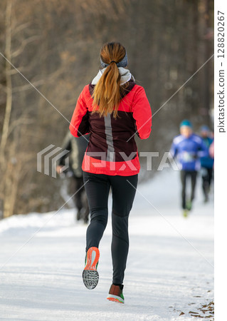 female runner participating in winter outdoor race marathon 128820267
