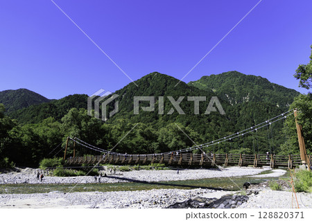 橫跨清澈溪流和鬱鬱蔥蔥的山巒的明神橋的夏季風景 橫跨清澈溪流和鬱鬱蔥蔥的山巒的明神橋的夏季風景 128820371