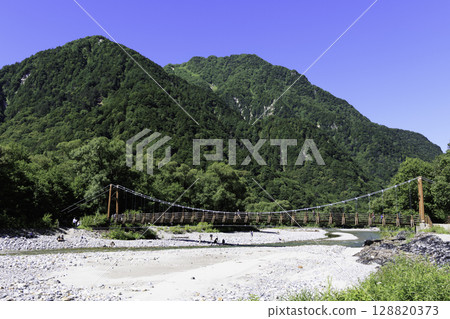 橫跨清澈溪流和鬱鬱蔥蔥的山巒的明神橋的夏季風景 128820373