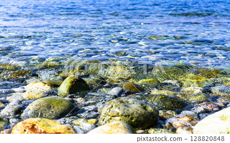 A photo of clear blue ocean waves gently lapping on the beach A photo of clear blue ocean waves gently lapping on the beach 128820848