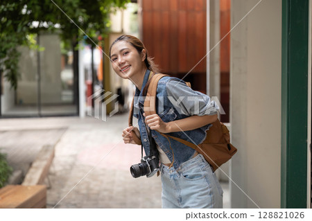 Smiling Young Woman with Camera and Backpack Smiling Young Woman with Camera and Backpack 128821026