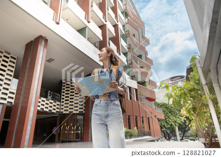 Adventurous woman navigating city with map Adventurous woman navigating city with map 128821027