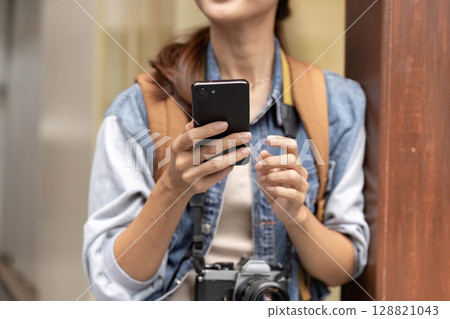 Young woman photographer using smartphone outdoors in urban setting 128821043