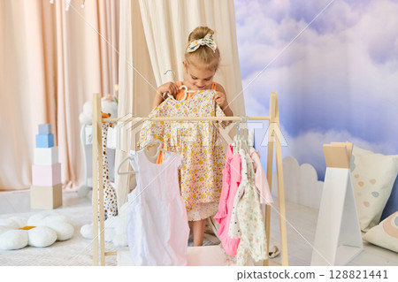 Little child girl choosing her clothes. Little child girl choosing her clothes. 128821441
