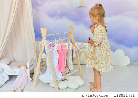 Little child girl choosing her clothes. Little child girl choosing her clothes. 128821451