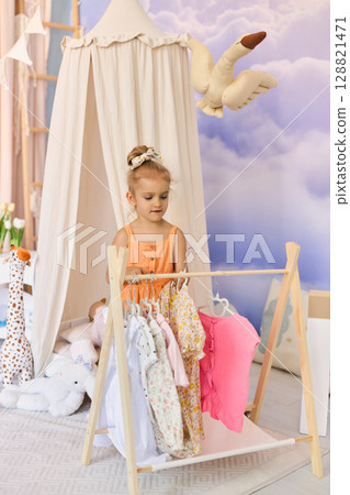 Little child girl choosing her clothes. Little child girl choosing her clothes. 128821471