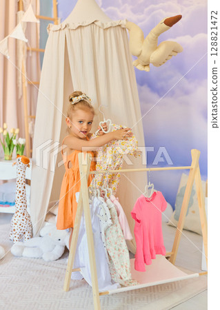 Little child girl choosing her clothes. Little child girl choosing her clothes. 128821472