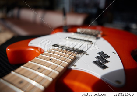 An orange electric guitar on top of a powerful amplifier 128821560