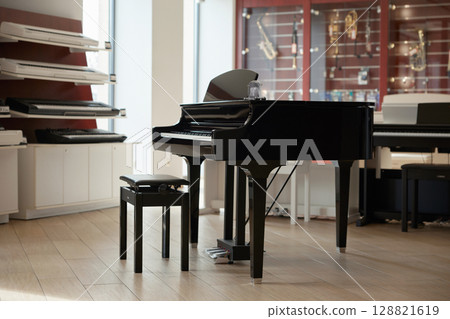 An elegant black grand piano on display in a modern music store for music enthusiasts 128821619