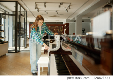 A woman wearing a stylish plaid shirt is standing beside a piano A woman wearing a stylish plaid shirt is standing beside a piano 128821644