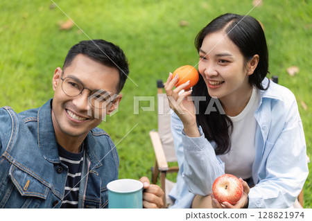 Cheerful couple sharing healthy snacks in a garden 128821974