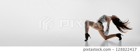 Energetic jazz funk dancer striking a pose on floor in heels against white backdrop. Banner 128822417