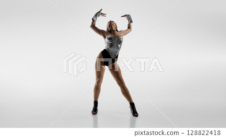 Dancer poses dramatically in metallic outfit and high heels on white background 128822418