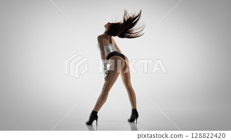 Energetic dancer in high heels strikes a dynamic jazz funk pose 128822420