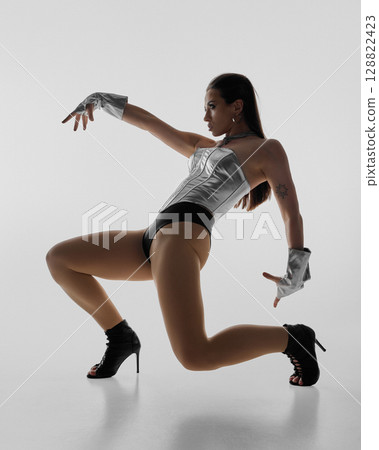 Dynamic jazz funk dancer striking a pose in high heels and metallic outfit 128822423