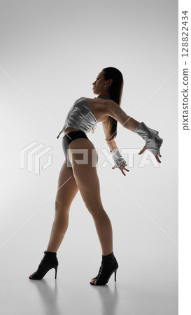 Dancer in silhouette striking pose wearing high heels and stylish dancewear Dancer in silhouette striking pose wearing high heels and stylish dancewear 128822434