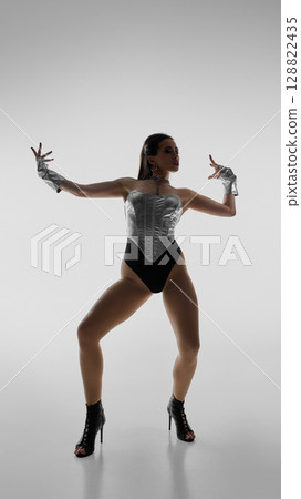 Elegant dancer striking dynamic pose in high heels against plain background 128822435