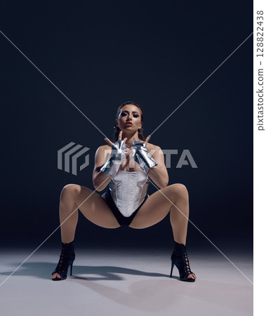 Dynamic jazz funk dancer in high heels striking a powerful pose on stage 128822438