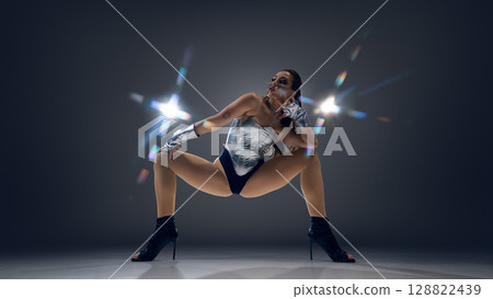 Dynamic jazz funk dancer striking a pose in stylish high heels with dramatic lighting 128822439