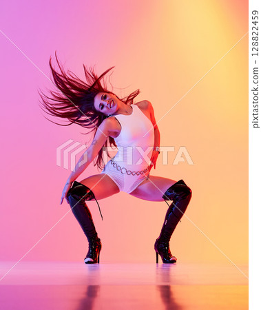 Jazz funk performer dressed in white attire wearing high heels with vibrant backdrop 128822459