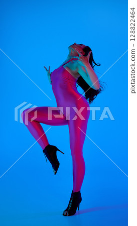 Dancer in vibrant pose with high heels and blue background 128822464