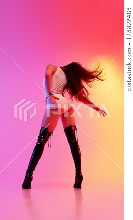 Jazz funk performer in high heels strikes a pose amidst vibrant lighting 128822483