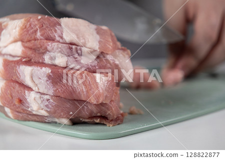 Stack of fresh raw pork meat slices on a green cutting board, prepared for cooking, showcasing healthy home food ingredients and culinary process Stack of fresh raw pork meat slices on a green cutting board, prepared for cooking, showcasing healthy home food ingredients and culinary process 128822877