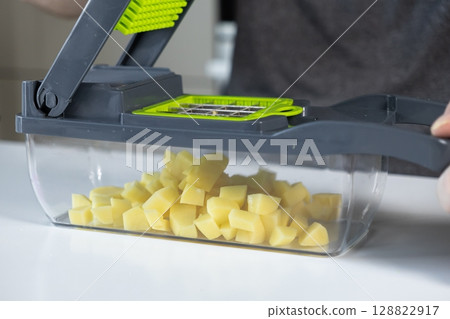 A modern kitchen vegetable dicer efficiently chops fresh potatoes into uniform pieces, simplifying home meal preparation and promoting healthy cooking A modern kitchen vegetable dicer efficiently chops fresh potatoes into uniform pieces, simplifying home meal preparation and promoting healthy cooking 128822917