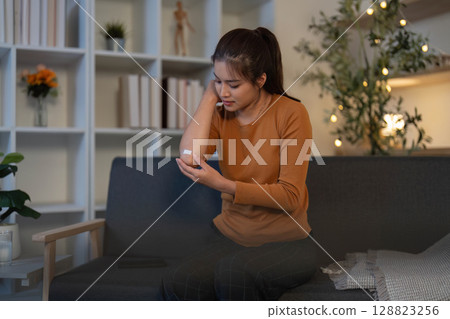 Health and Wellness. Young woman checking her health status at home with a smartwatch. Health and Wellness. Young woman checking her health status at home with a smartwatch. 128823256
