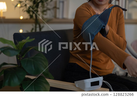 Health Monitoring. Woman measuring blood pressure at home. 128823266