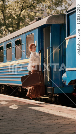Woman in vintage outfit boarding blue train with suitcase and joyful expression Woman in vintage outfit boarding blue train with suitcase and joyful expression 128823299