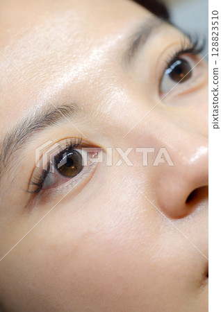 Young southeast asian woman undergoing an eyelashes extension procedure in beauty salon. calm female eyes show natural beauty health and wellness after makeup treatment Young southeast asian woman undergoing an eyelashes extension procedure in beauty salon. calm female eyes show natural beauty health and wellness after makeup treatment 128823510