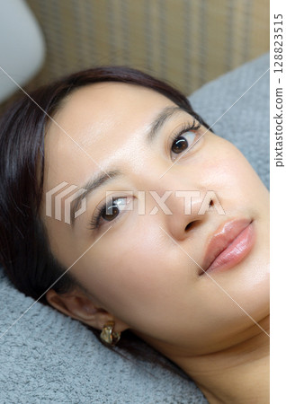 Young southeast asian woman in beauty salon during an eyelashes extension procedure for natural beauty. female eyes show sense of health wellness and calm with no makeup 128823515