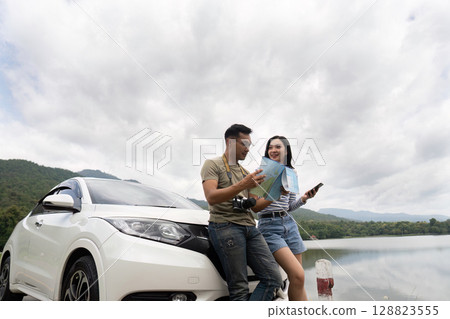 Couple exploring nature with map by car near lake Couple exploring nature with map by car near lake 128823555