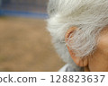 The elderly man's white hair is starting to grow long. 128823637