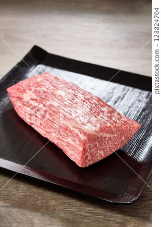 奢華食材的照片，一塊A5級黑毛和牛大腿肉盛放在黑色的方形盤子裡 128824704