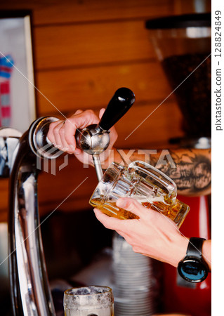 Bartender pours ice-cold beer into a glass. Summer evening 128824849