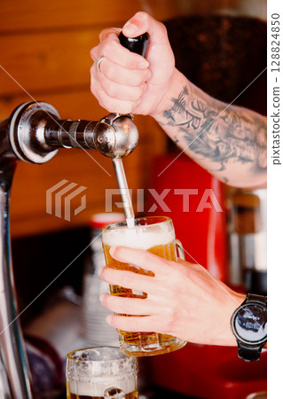 Bartender pours ice-cold beer into a glass. Summer evening 128824850
